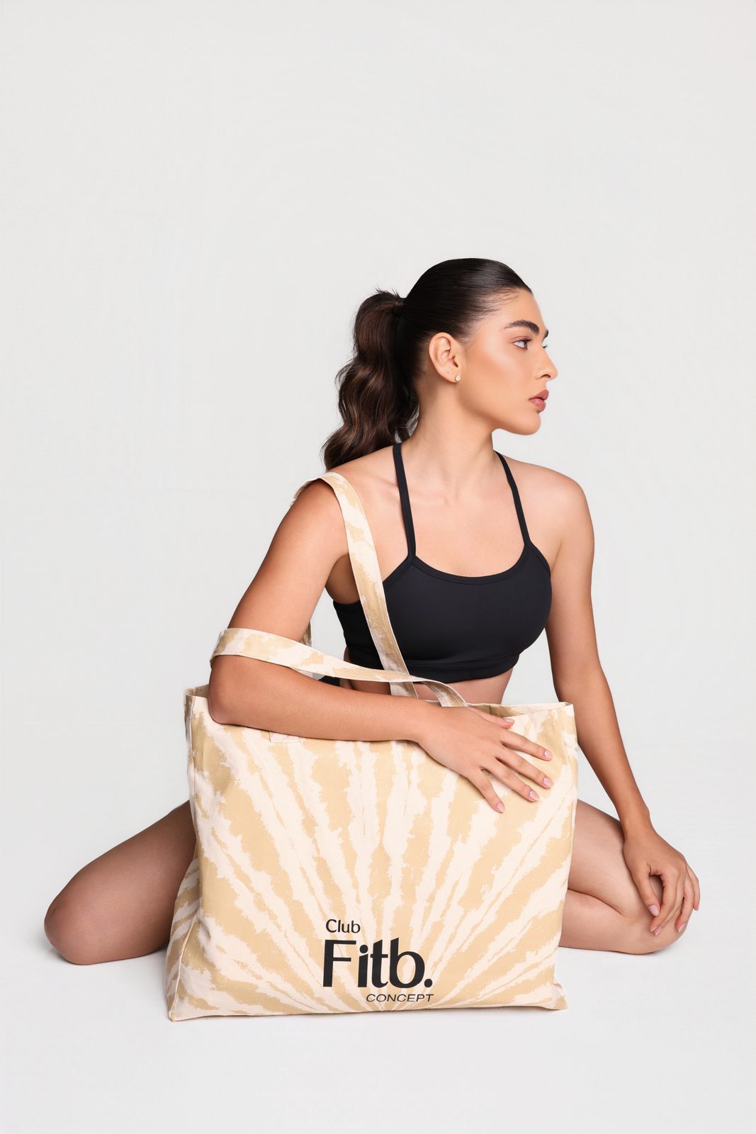 Mulher com top preto segurando a bolsa Club Fitb. Concept