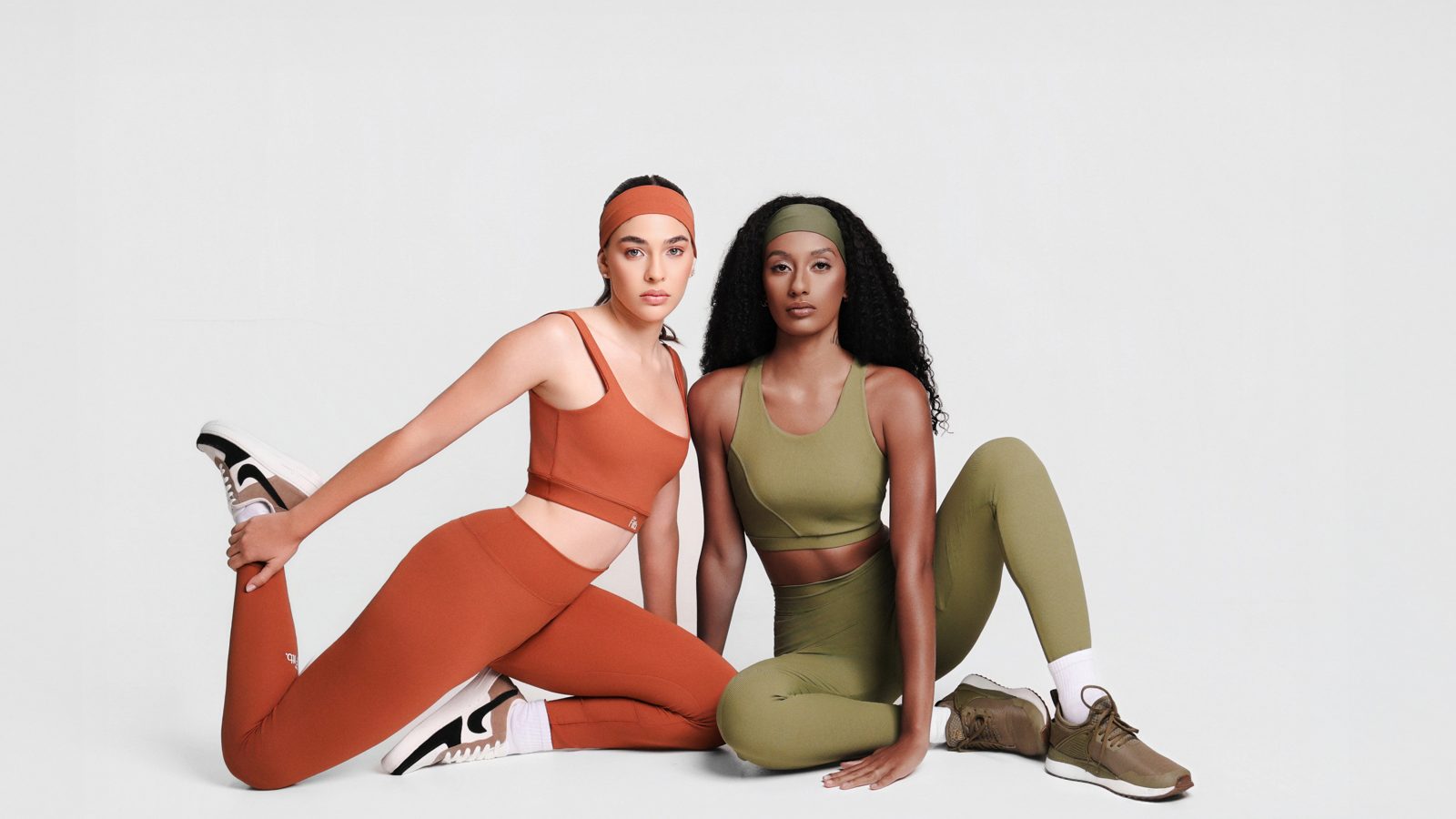 Duas mulheres com conjuntos fitness terracota e verde oliva